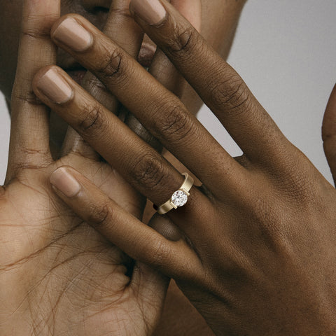 Close view of round brilliant diamond in partial bezel on wide flat band