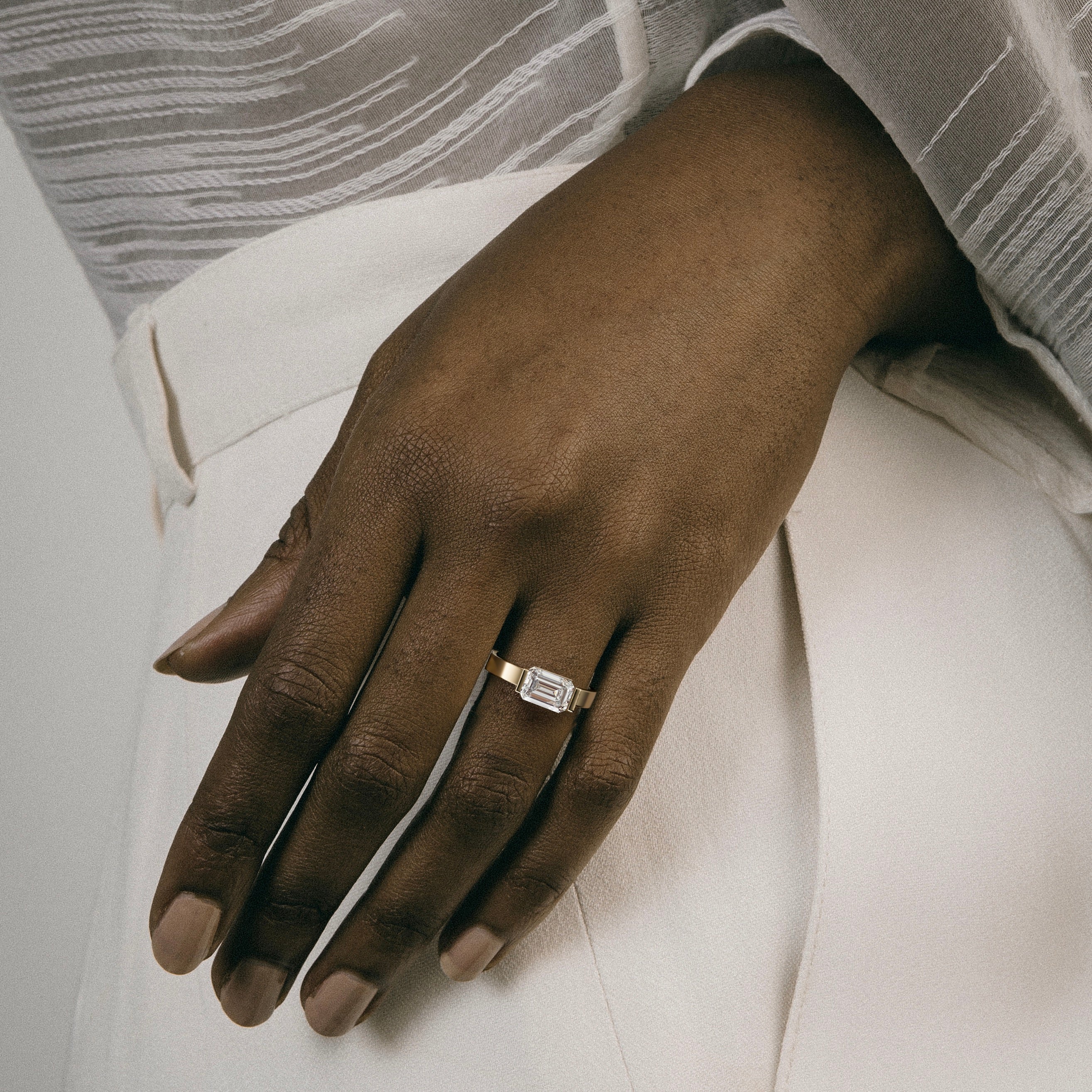 close view of 2.00 ct emerald-cut diamond engagement ring set east-west in tapering partial bezel on wide band