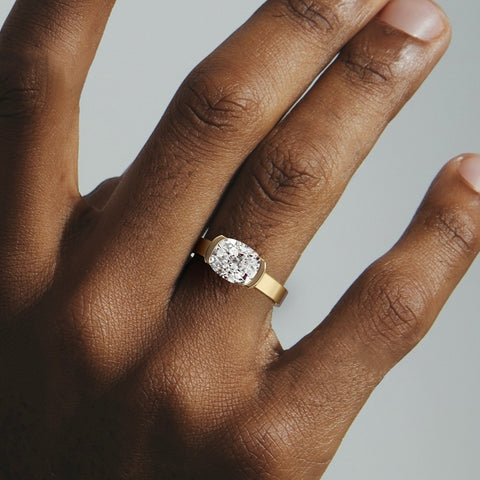 close view of 2.00 ct cushion diamond set east-west in tapering partial bezel on sculptural band