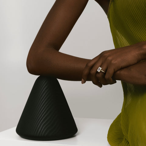 2.50 carat emerald-cut diamond bezel engagement ring on slim domed gold band worn on hand