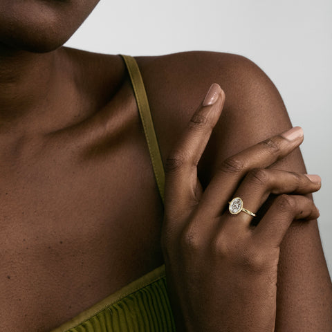 1.50 carat oval diamond bezel engagement ring on slim domed gold band worn on hand