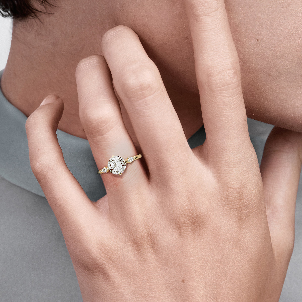 Close view of round brilliant diamond three stone engagement ring with pear-cut accent stones on delicate round band