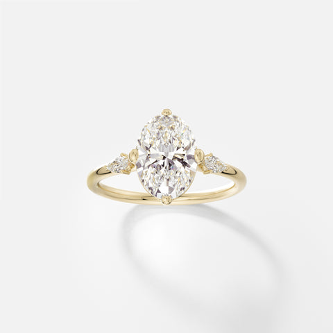 14k yellow gold three stone engagement ring with 2.00 carat oval diamond and pear-cut side stones on delicate round band