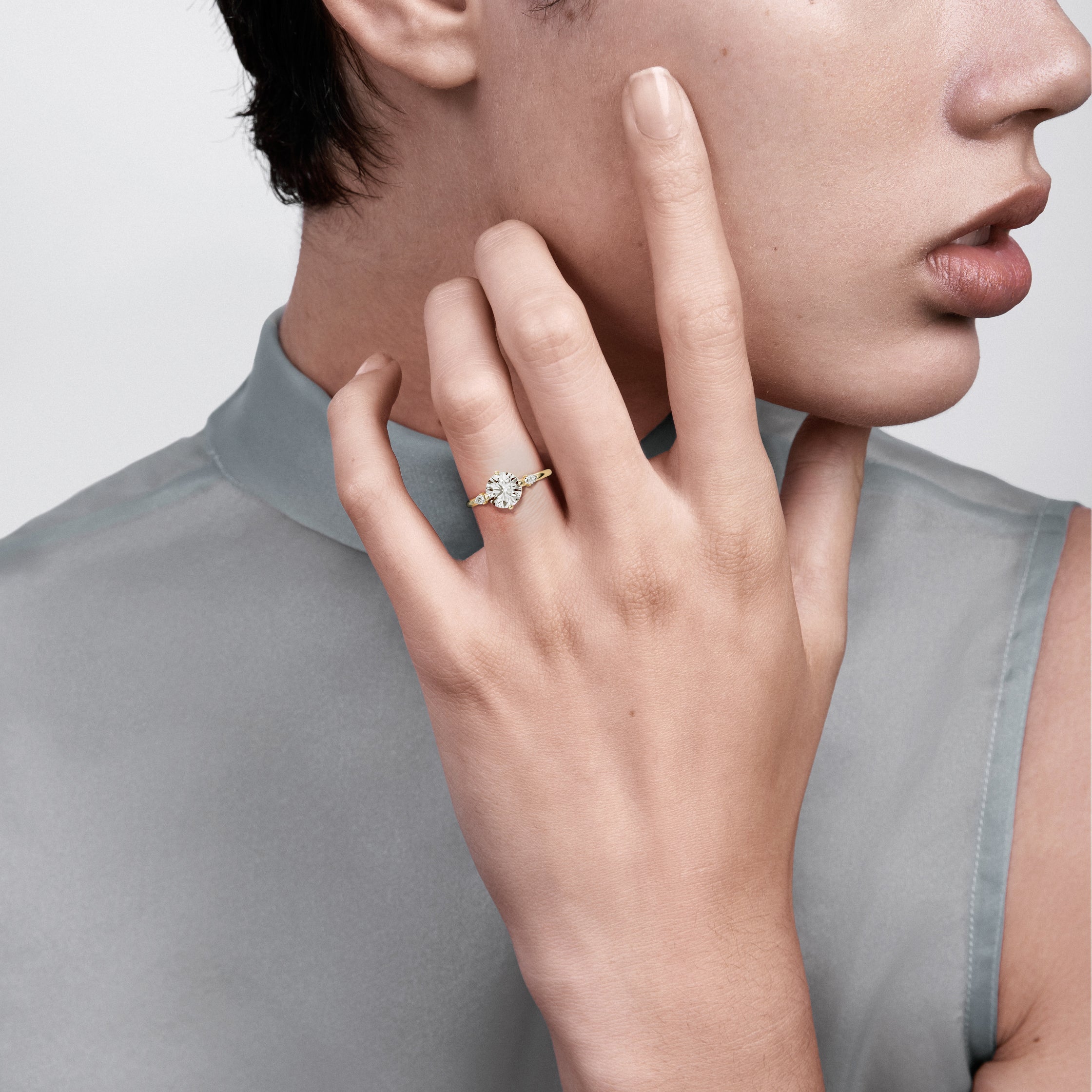 14k yellow gold three stone engagement ring with round brilliant diamond in compass prongs and pear accent stones worn on hand