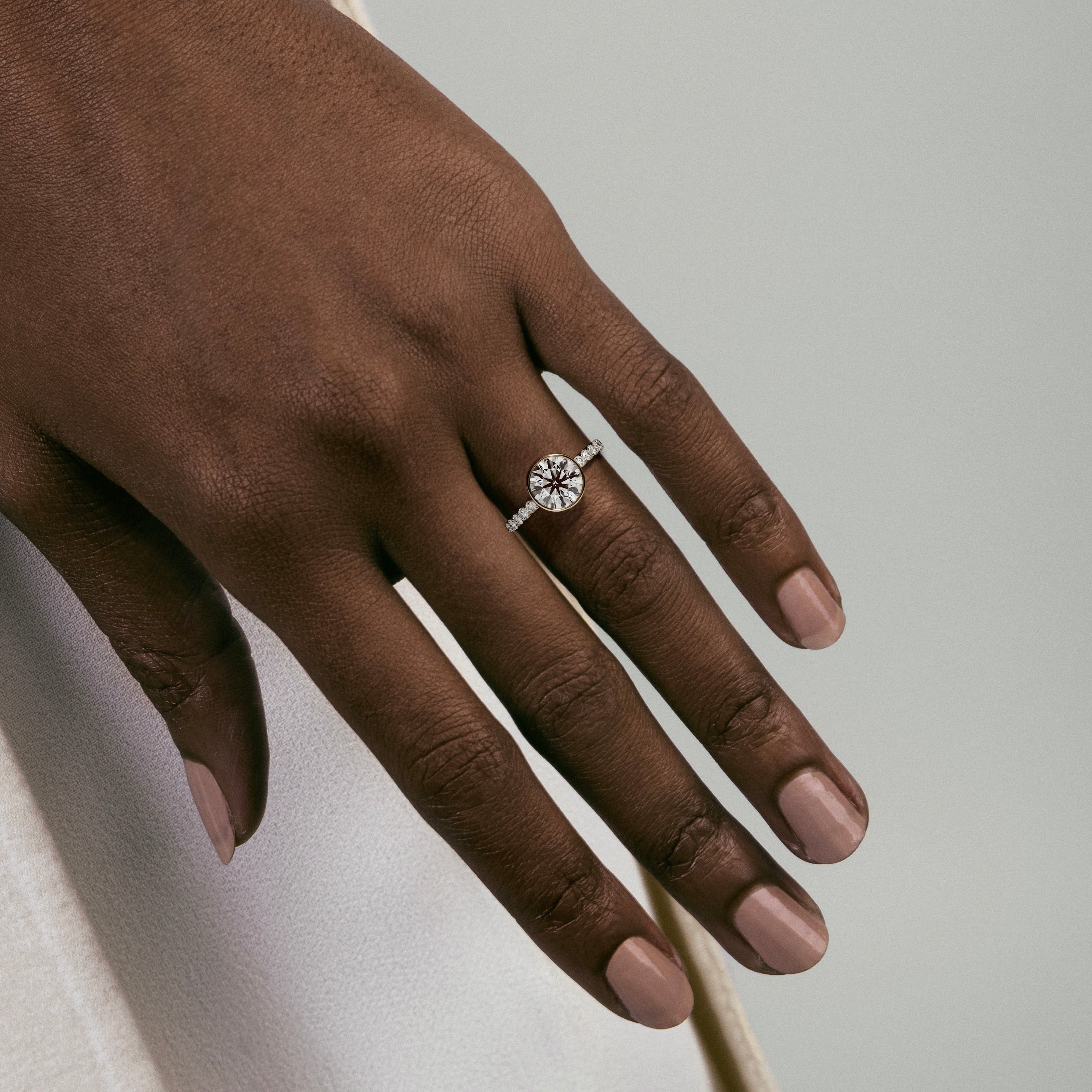 Close view of bezel set diamond engagement ring with pavé diamond half eternity band