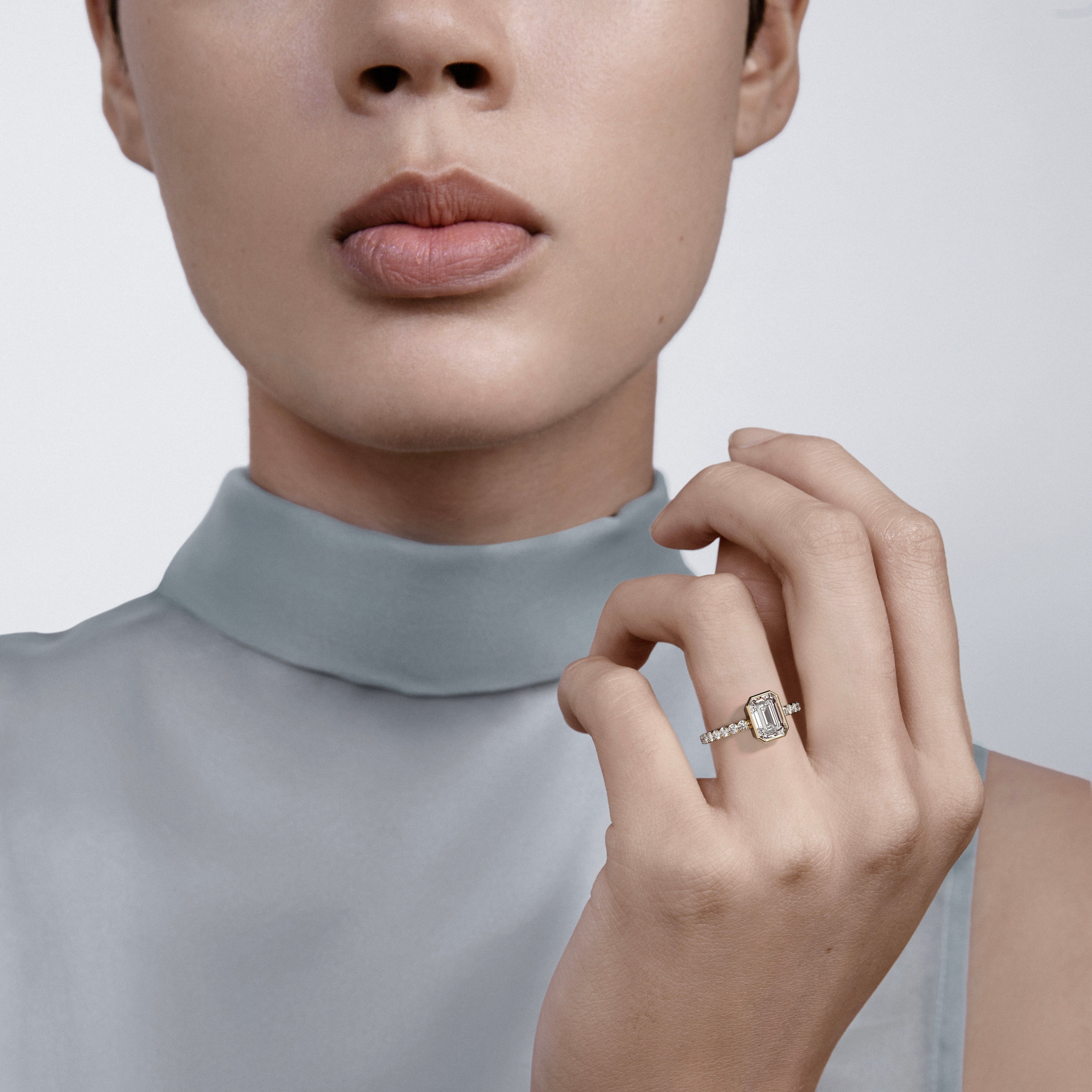 14k yellow gold engagement ring with emerald-cut diamond and pavé diamond band worn on hand