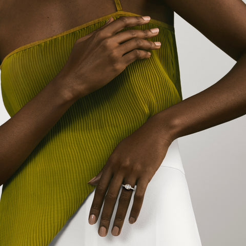 Tulpe oval diamond bezel pavé engagement ring worn on hand