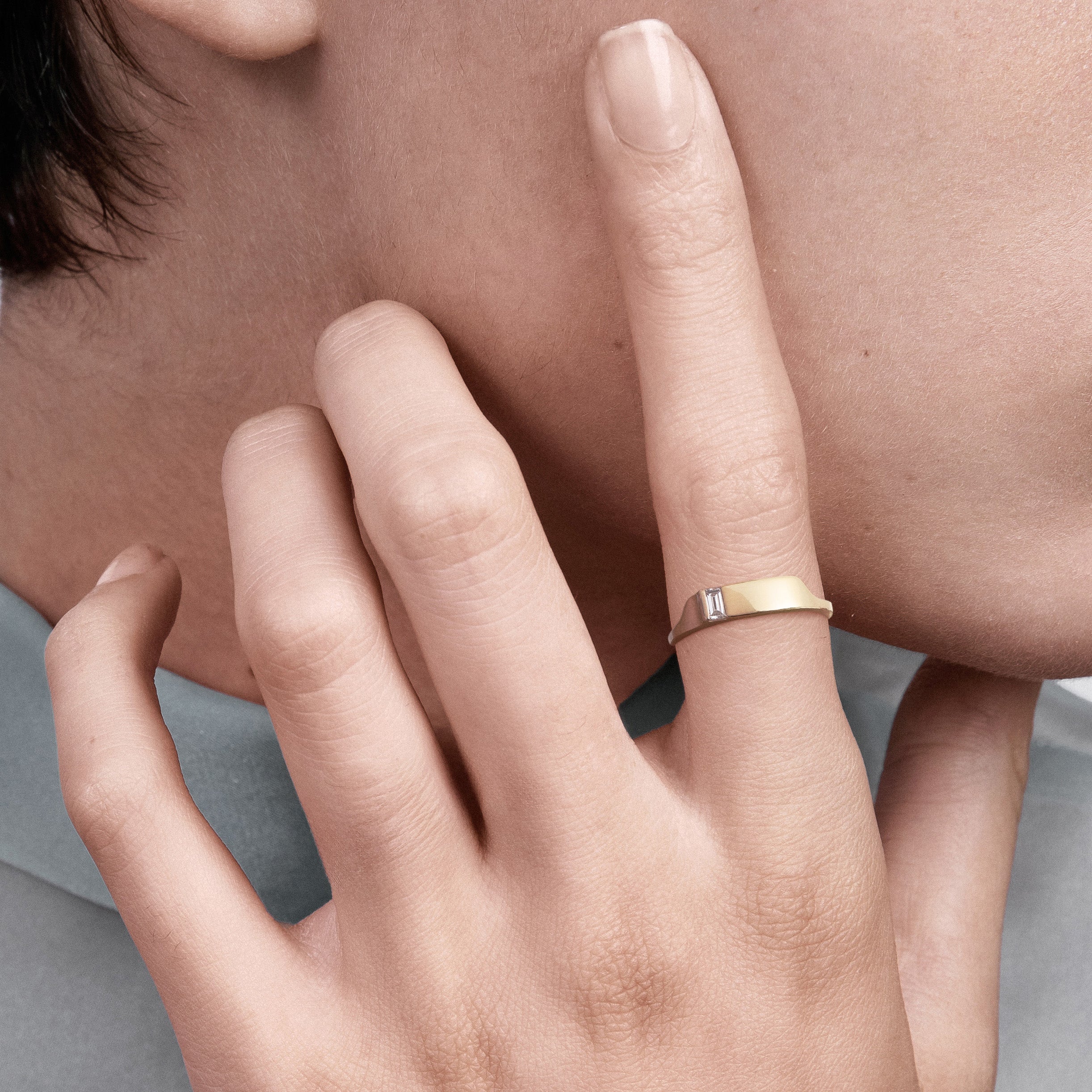 Architectural gold ring with baguette diamond worn on hand