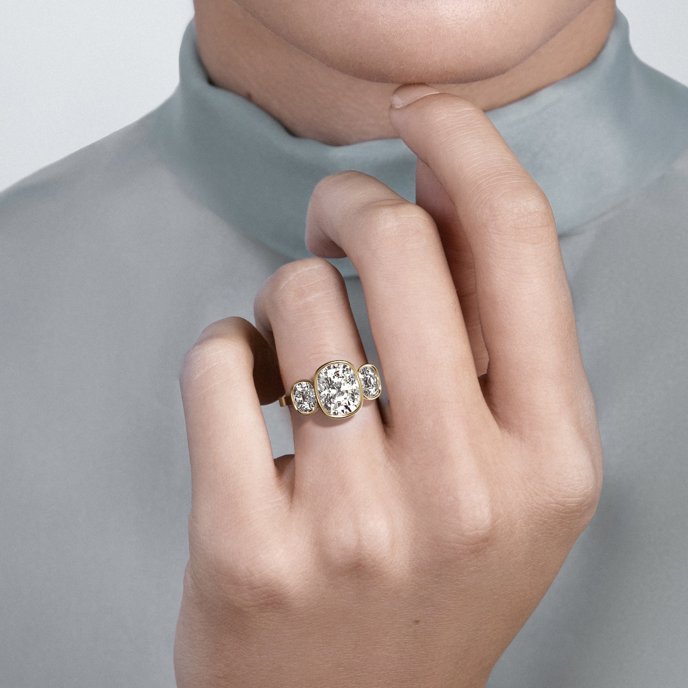 Close view of three stone engagement ring with elongated cushion center diamond and side stones on flat band