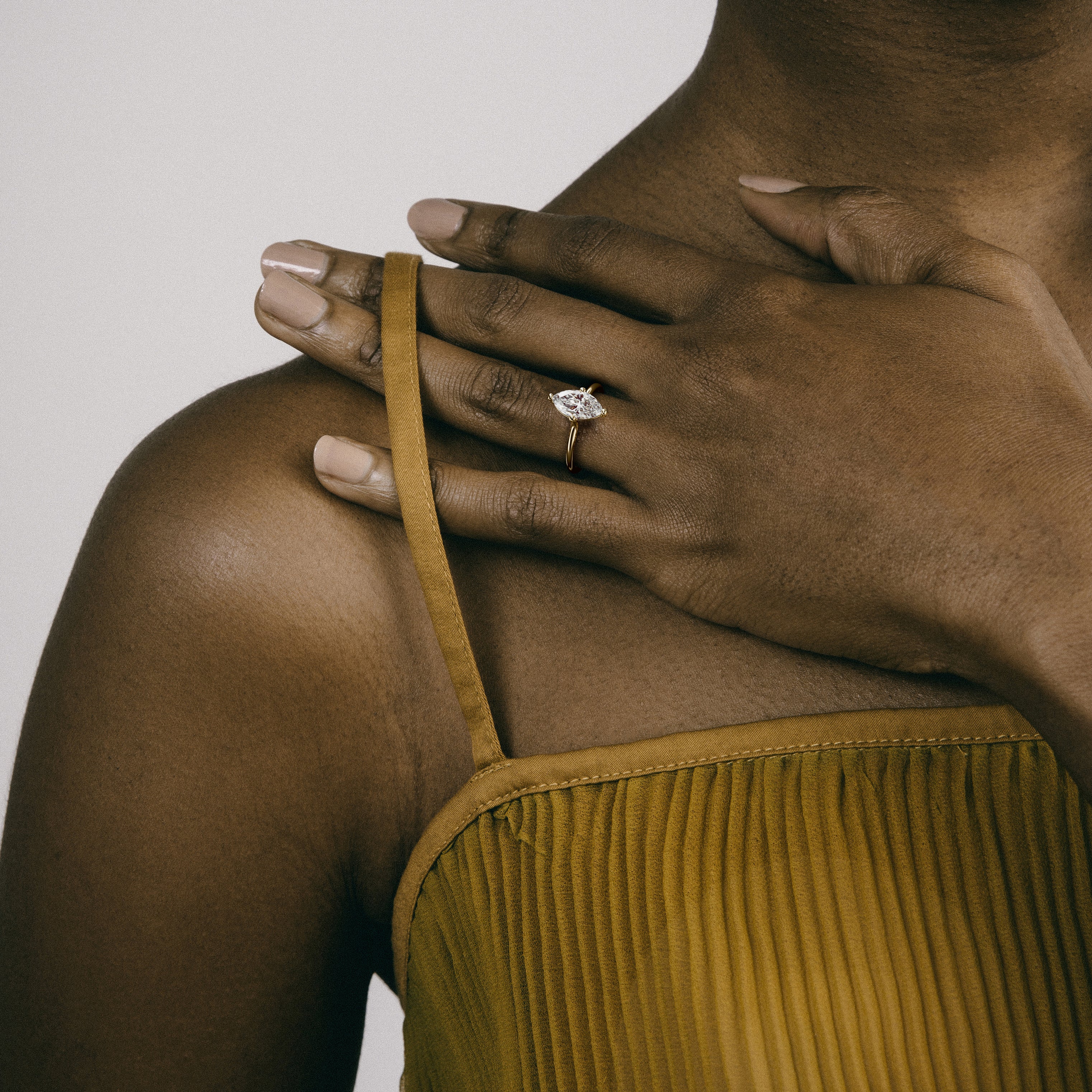 Dainty yellow gold engagement ring with marquise diamond worn on hand