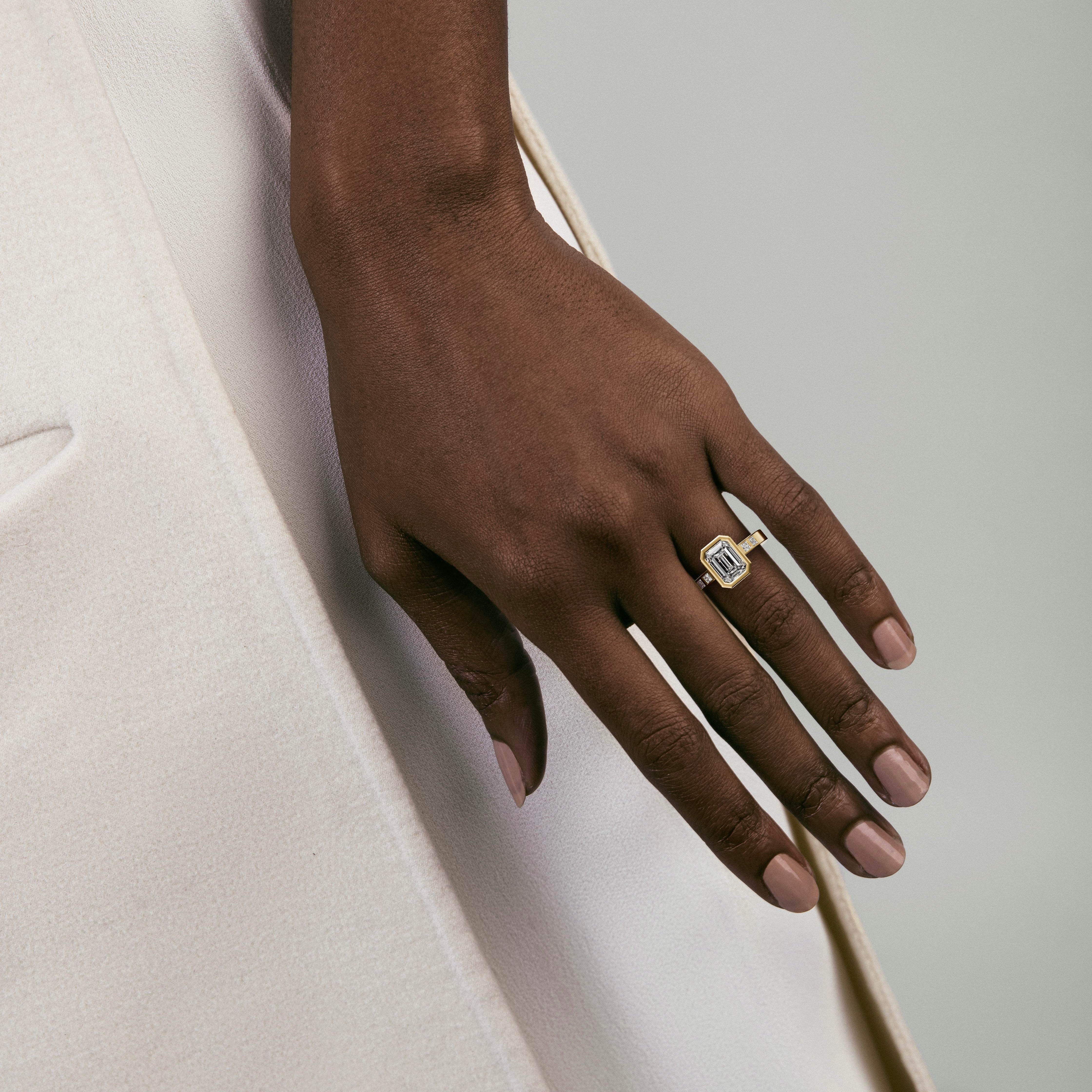 emerald-cut diamond engagement ring with princess-cut diamonds set along the band worn on hand