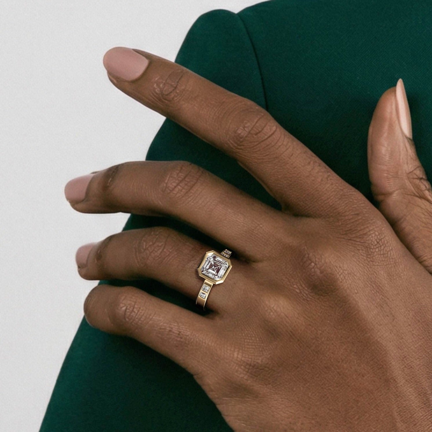 close view of square emerald cut diamond engagement ring with princess-cut diamonds flanking the center stone