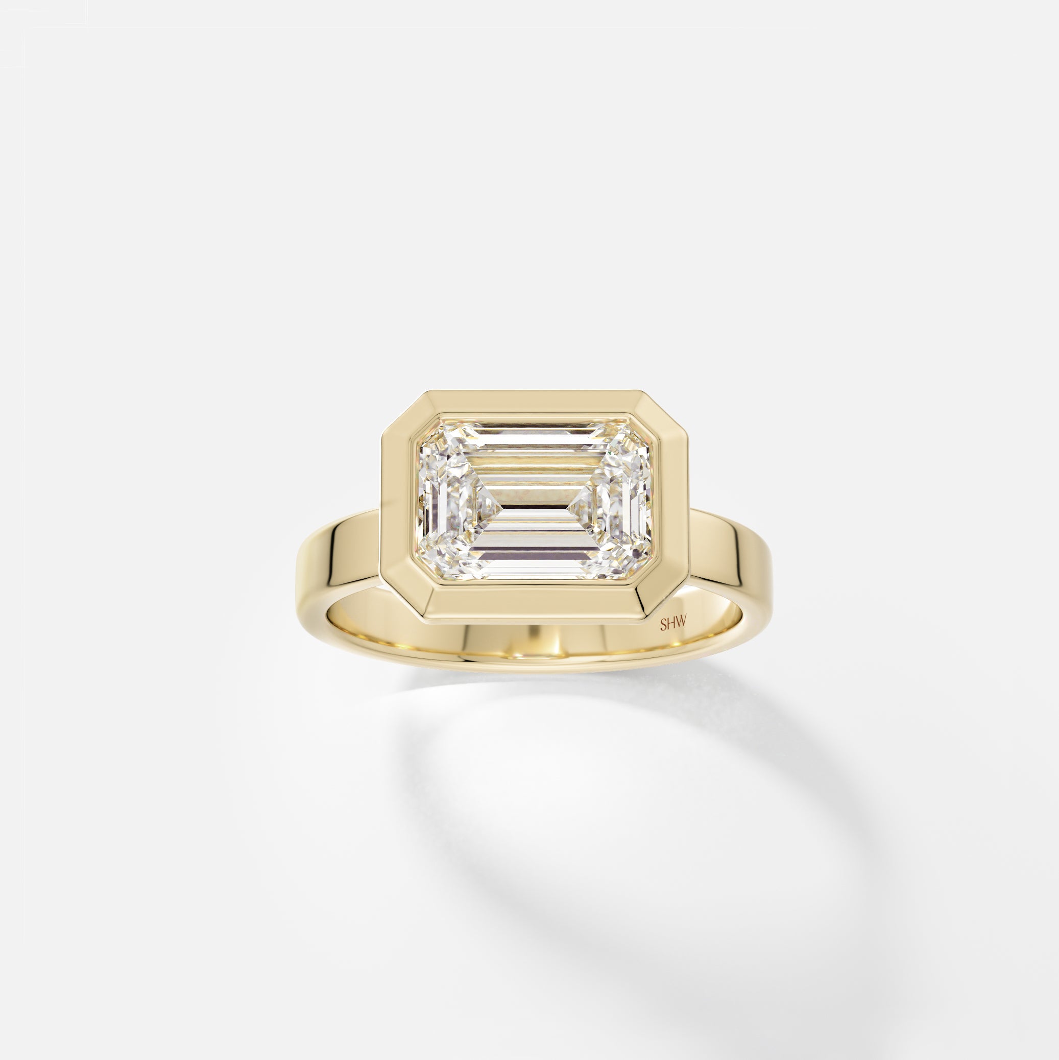 14k yellow gold wide flat band engagement ring with 2.50 carat east west emerald-cut diamond in thick bezel