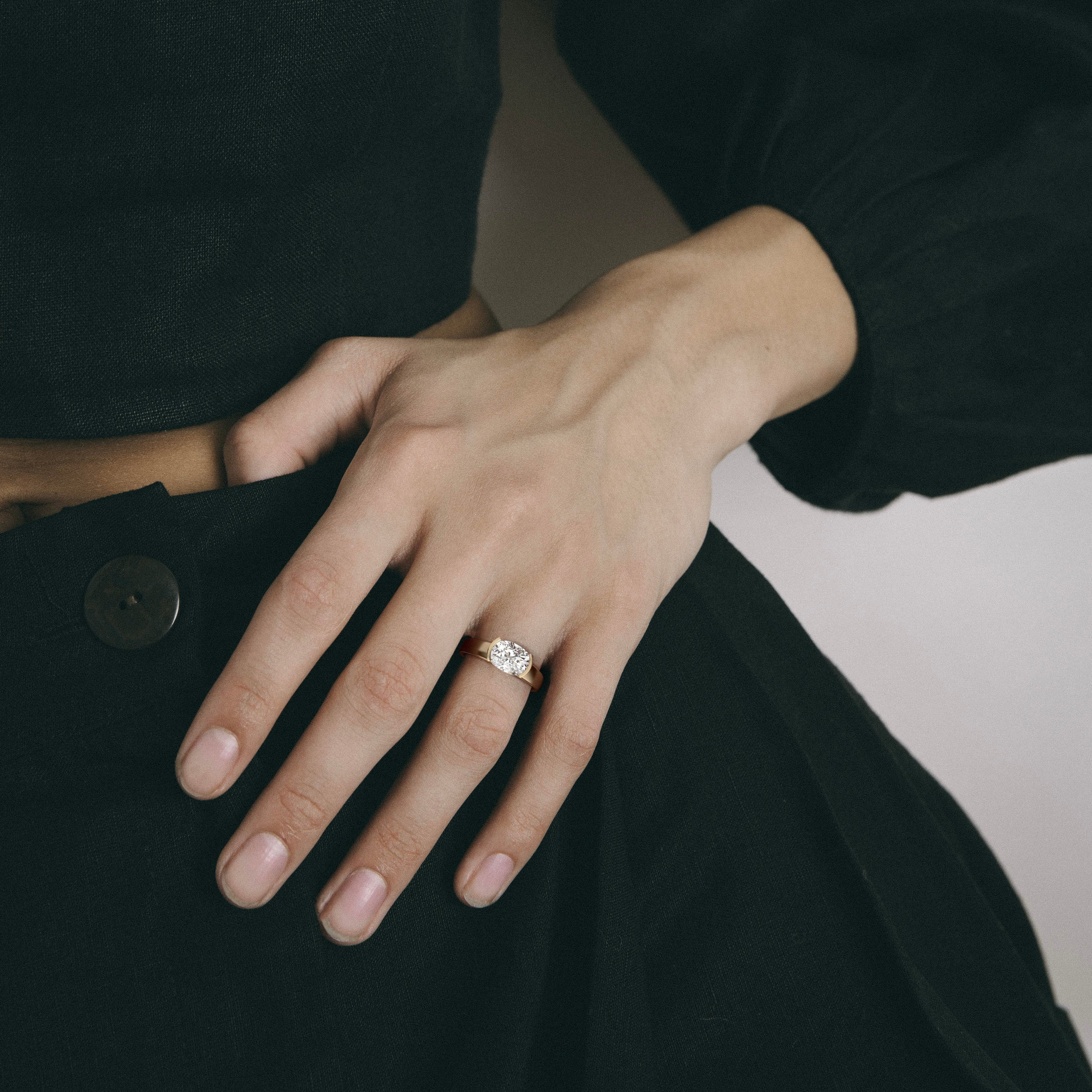 2.00 carat east-west cushion diamond engagement ring with tapering partial bezel worn on hand