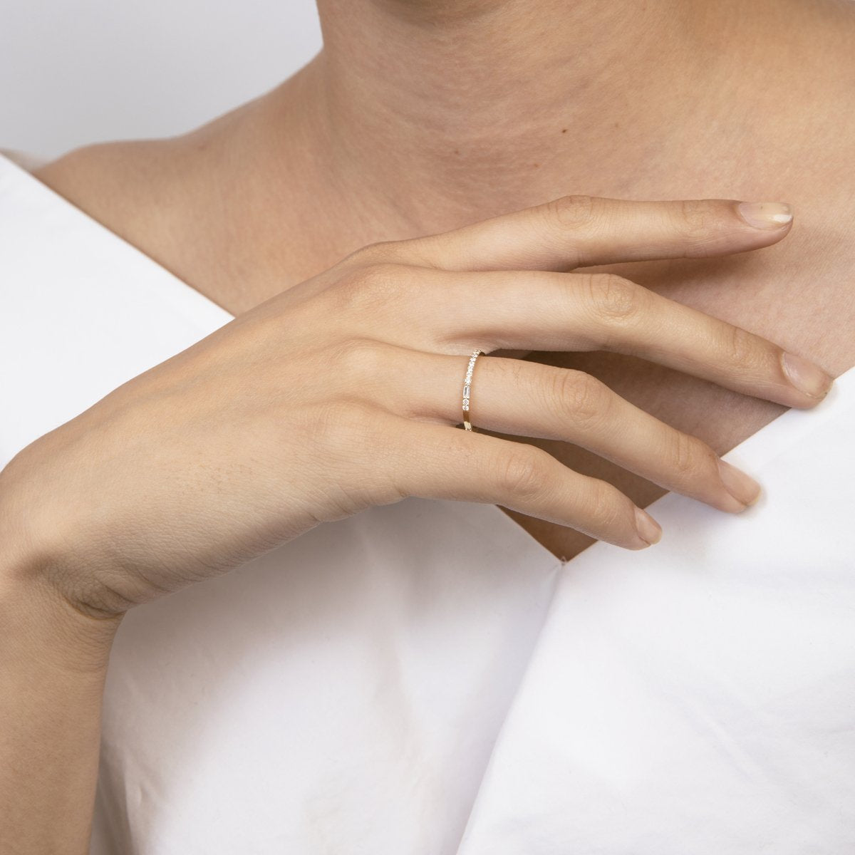 Thin asymmetrical diamond wedding band worn on hand