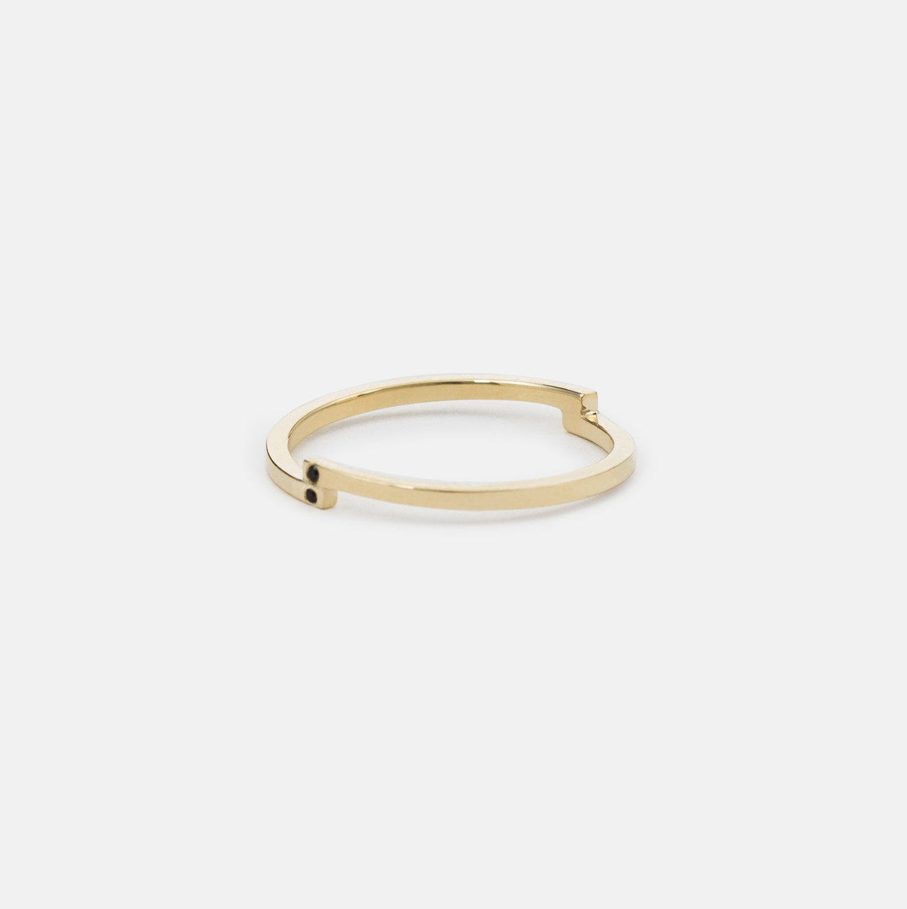 Slim gold wedding band showing offset black diamond placement 