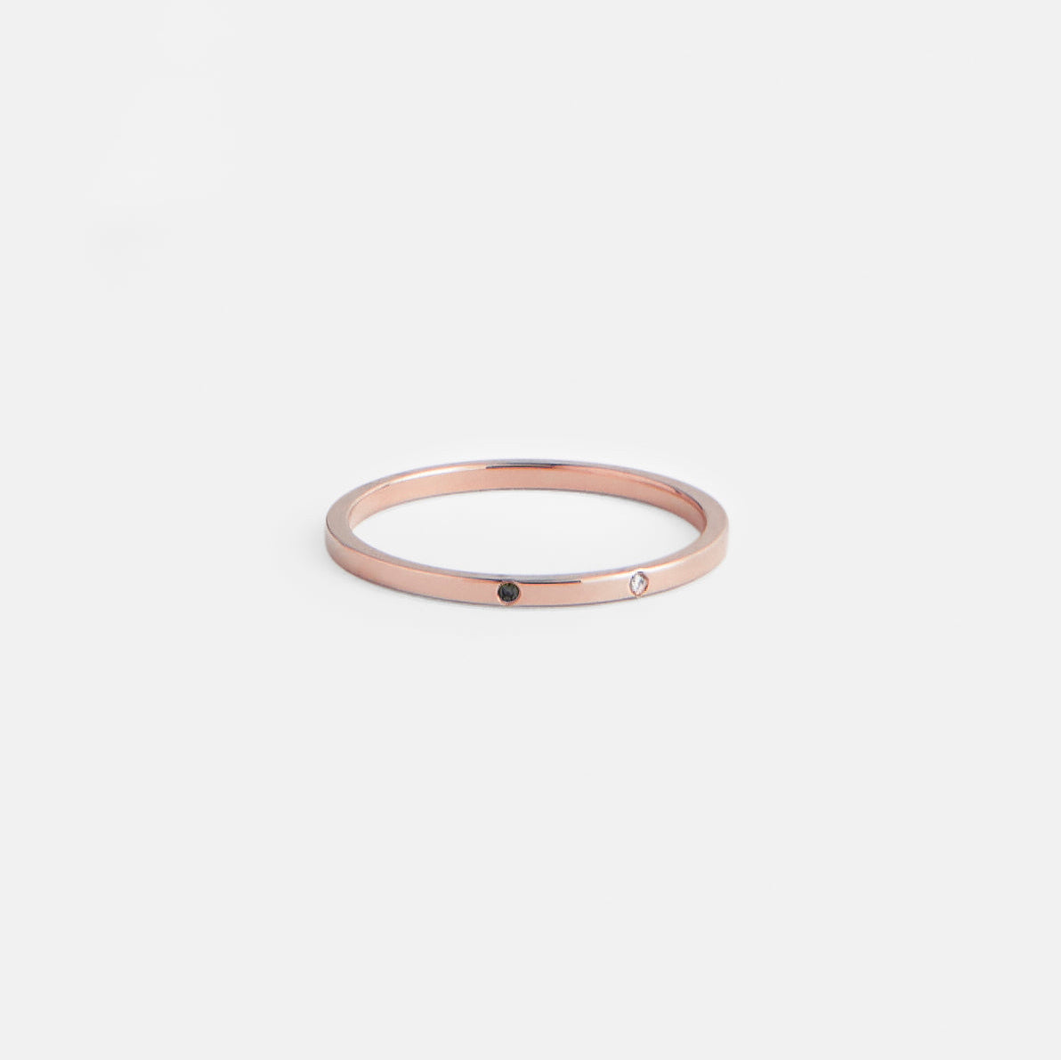 14k rose gold delicate wedding band with one white and one black diamond